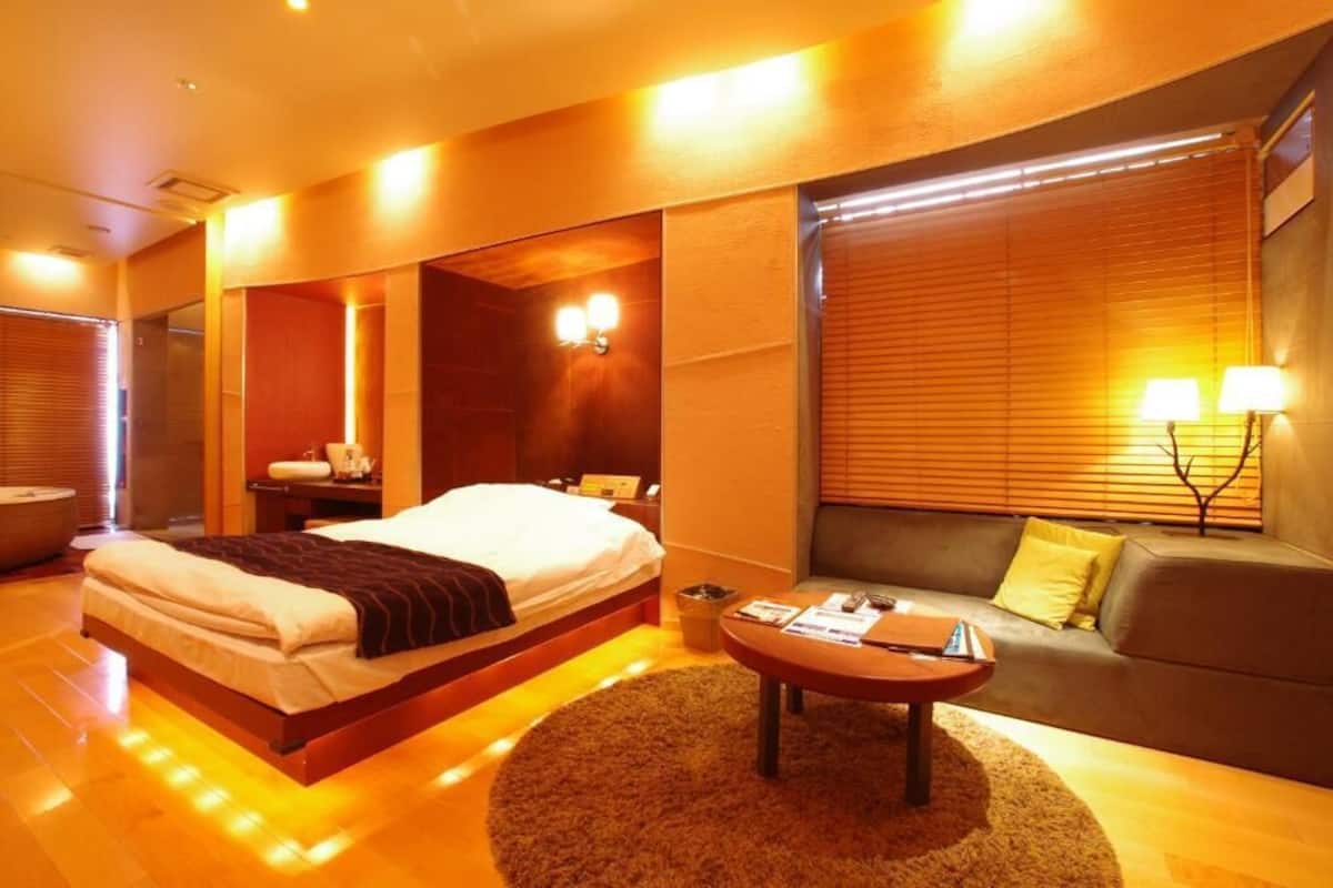 Une chambre d’hôtel avec un lit, un canapé, une table basse et une lampe.