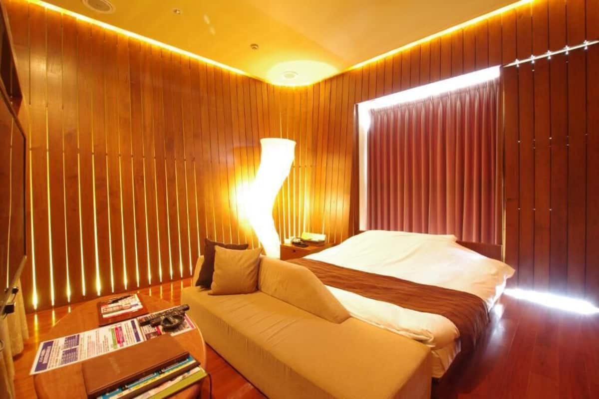 Une chambre d’hôtel avec un lit, un canapé, une table de chevet et une lampe.