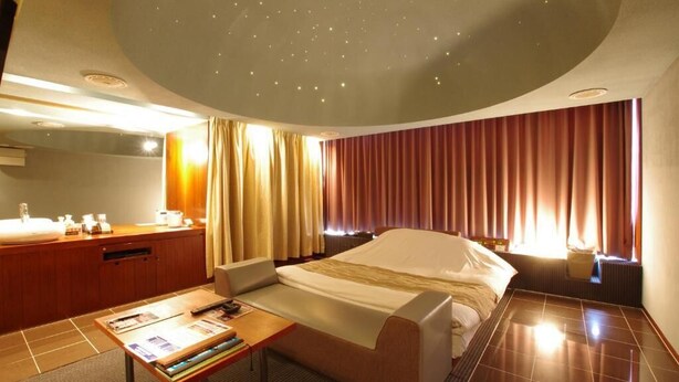Ein Hotelzimmer mit Bett, Schreibtisch, Stuhl, Schminktisch und Vorhängen.