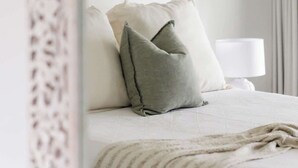 A bedroom with a bed, pillows, a lamp, and a painting on the wall. - A Noosa Gem on Noosa Parade - close to everything (Noosa Heads)