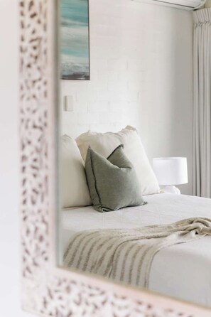 Ein Schlafzimmer mit einem Bett, Kissen, einer Lampe und einem Bild an der Wand.