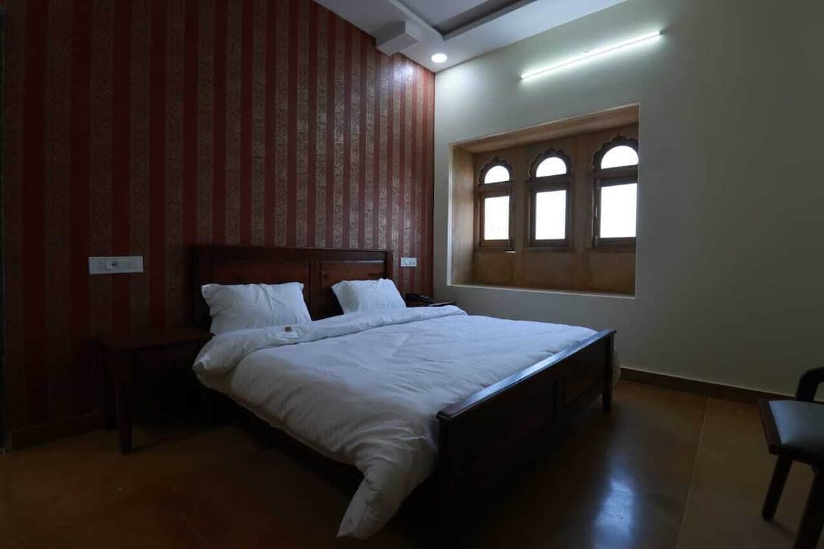 Een slaapkamer met een bed, een raam met een gebogen ontwerp en een gestreepte wand.