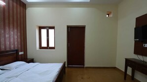 Quarto com cama, janela, porta e TV fixada na parede.