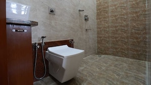 Casa de banho com sanita, chuveiro e lavatório.