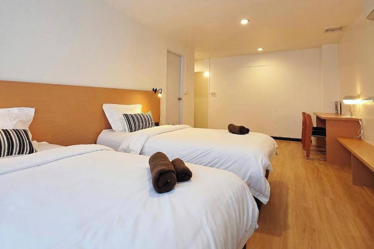 A hotel room with two beds, a desk, and a chair.