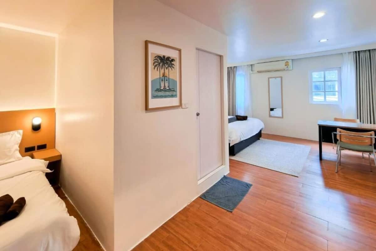 A hotel room with a bed, bedside table, nightstand, desk, chair, and a window with curtains.