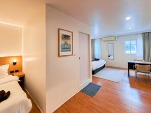A hotel room with a bed, bedside table, nightstand, desk, chair, and a window with curtains. - Baan Rak (Bangkok)
