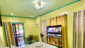 A hotel room with a bed, a TV, a desk, and a chair. - Lens Staycation Serene 2-BDR-1BR-KTCHN-Wifihouse with AC in peaceful Panabo (Panabo)