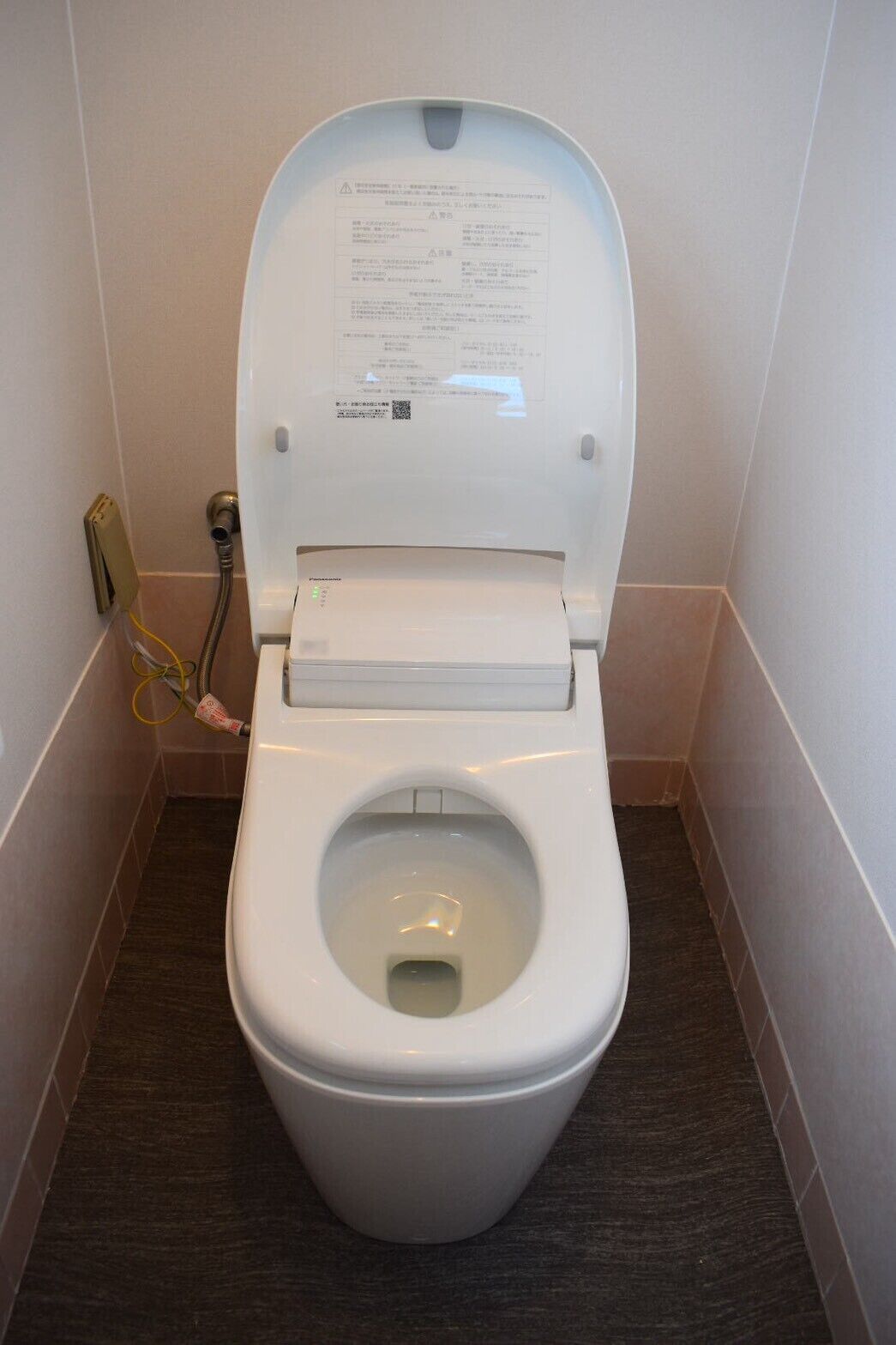 A white toilet with a closed lid, a visible water tank, and a paper with instructions on the tank.