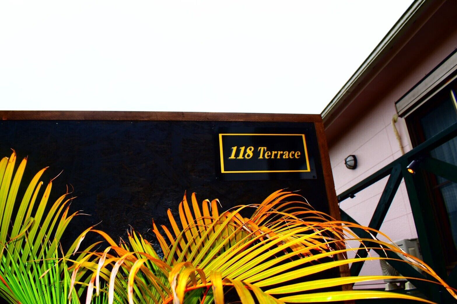 A building with a sign reading '118 Terrace' and a plant in the foreground.