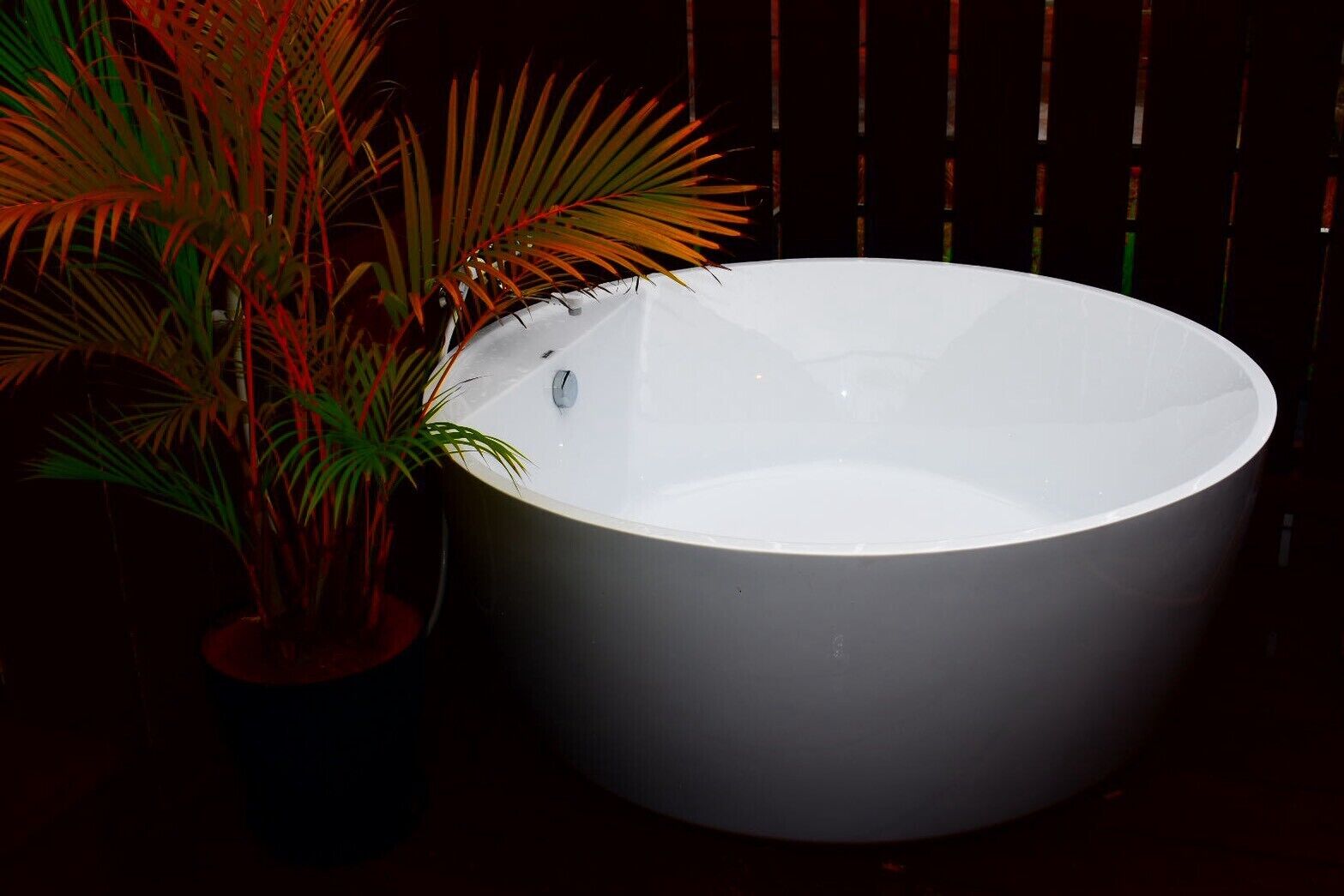 A large white bathtub next to a potted plant.