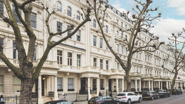 A row of traditional white buildings with large windows and a tree in the foreground. - Elegant South Kensington Retreat (London)
