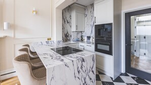 A modern kitchen with marble countertops, a built-in oven, and a black and white tiled floor. - Elegant South Kensington Retreat (London)