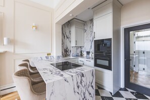 A modern kitchen with marble countertops, a built-in oven, and a black and white tiled floor. - Elegant South Kensington Retreat (London)