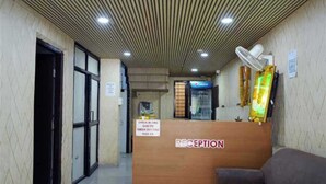 A reception area with a wooden desk, a couch, and a Pepsi refrigerator. - Hotel The Cozy Stay (Indore)