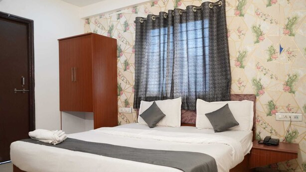 A bedroom with a bed, a wardrobe, a nightstand, a telephone, and a curtain. - Hotel The Cozy Stay (Indore)