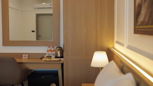 A hotel room with a wooden desk, a chair, a lamp, a refrigerator, a mirror, and a door. - B2 Future Park Rangsit Boutique & Budget (Thanyaburi)