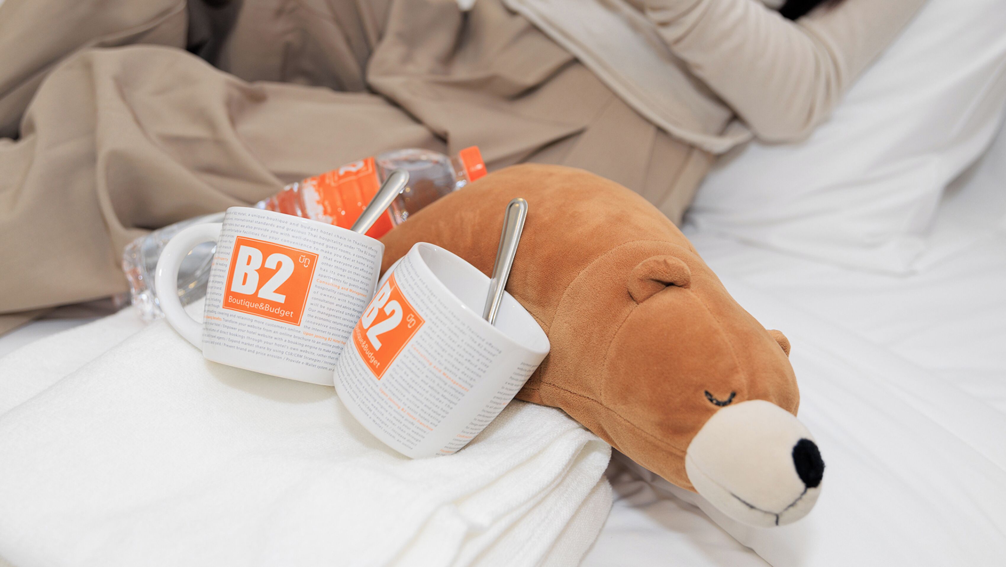 Un peluche, dos tazas y una botella sobre una cama.