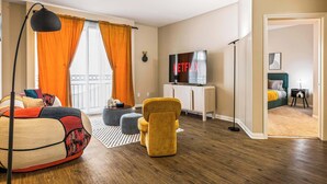 A modern hotel room with a sofa, a yellow armchair, a TV, and a balcony with orange curtains. - Fable 2Bd-2Ba MarinaDelRey Parking, Pool & Jacuzzi (Marina del Rey)