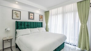 A neatly made bed with a green headboard, a bedside table with a lamp, and three framed pictures on the wall. - Stylish, fully equipped apartment in the prime area of Westlands, Nairobi (Nairobi)