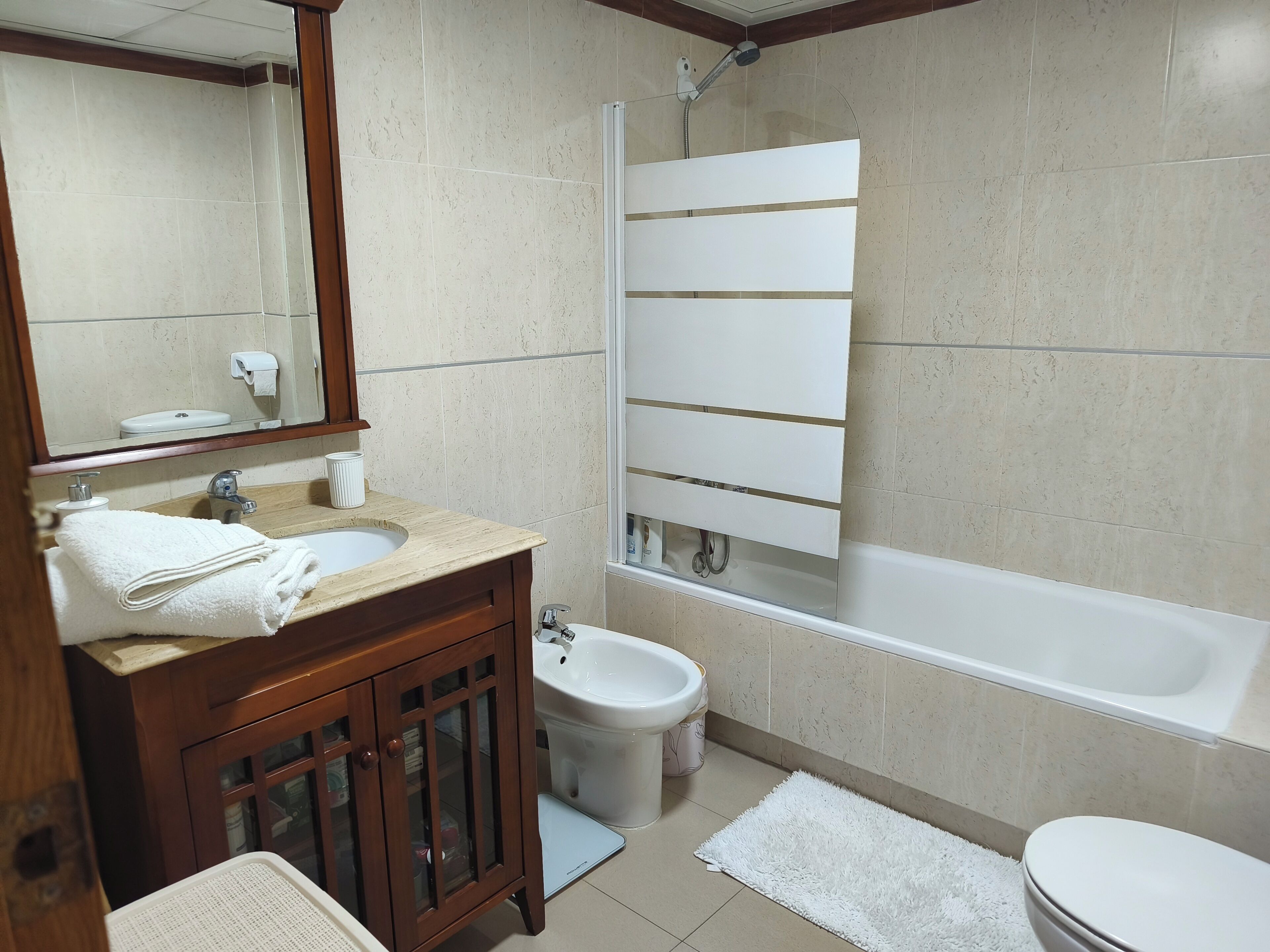 A bathroom with a sink, mirror, cabinet, toilet, bidet, and bathtub.