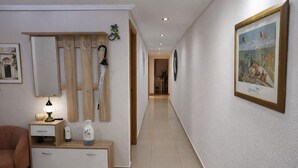 Ein Flur mit einer hölzernen Bank, einer Lampe, einem gerahmten Bild und einer Tür.