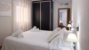 Ein Hotelzimmer mit einem Bett, einem Kleiderschrank, einem Nachttisch mit Lampe und einem Fenster mit Vorhängen.