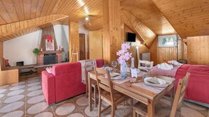 Un interno in legno accogliente con un tavolo da pranzo apparecchiato per due, un divano rosso e un caminetto.