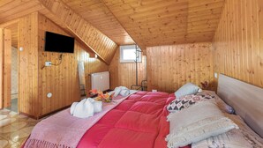 Una stanza con rivestimento in legno, un letto, una televisione e una finestra.