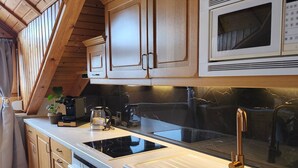 A kitchen with wooden cabinets, a built-in microwave, a stainless steel sink, and a black countertop. - Vacation apartment Burgzauber (Burghausen)