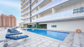 A rooftop pool area with lounge chairs and a swimming pool. - Free Housekeeping Visits During Your Stay - Stayshort - Cozy Studio in Sposrt City That Sleeps 3 (Dubai)