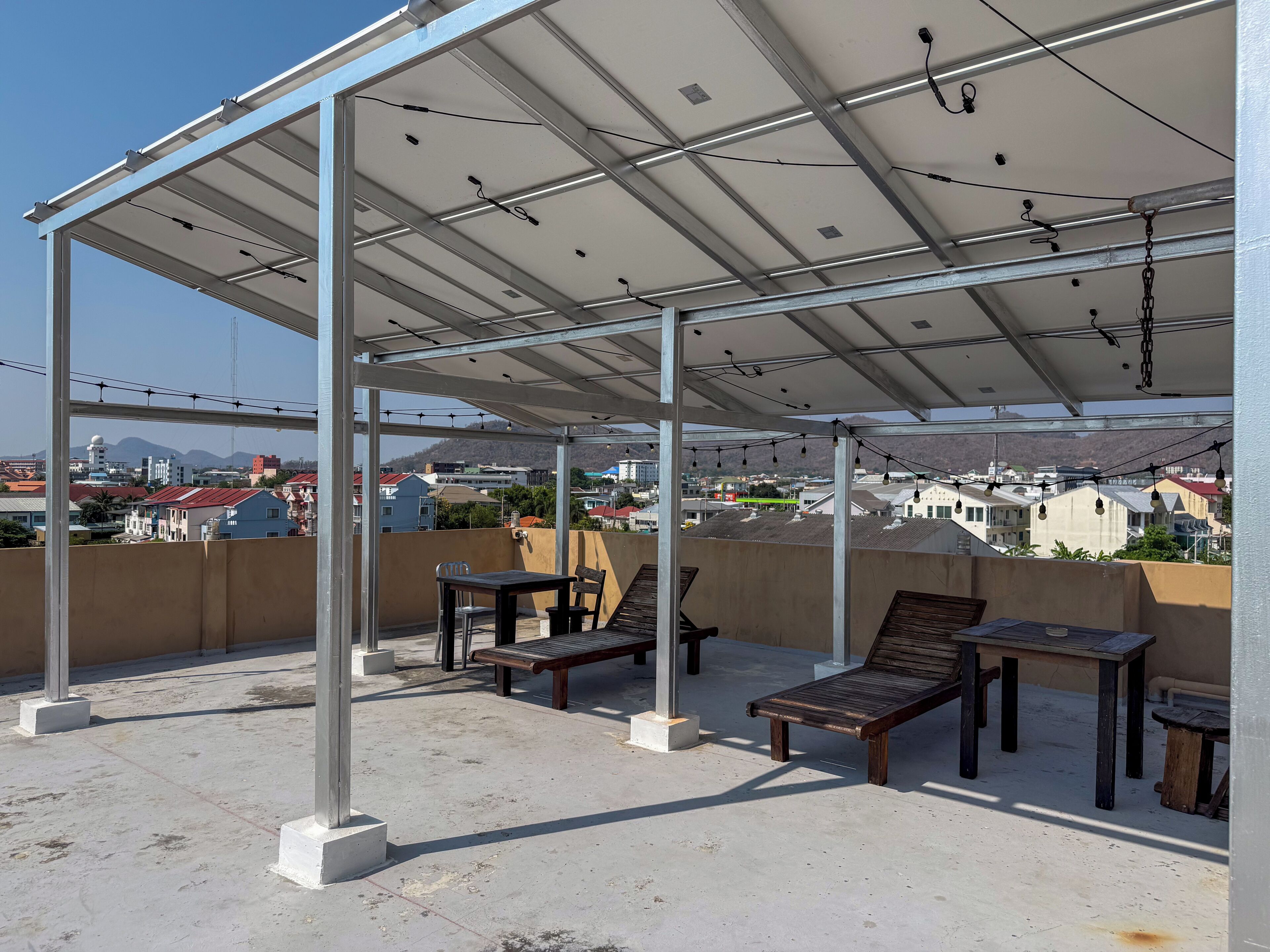 Une terrasse sur le toit avec un espace salon couvert, une table et des chaises.