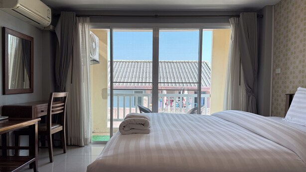 Une chambre d’hôtel avec un lit, un bureau, une chaise et une vue sur l’extérieur.