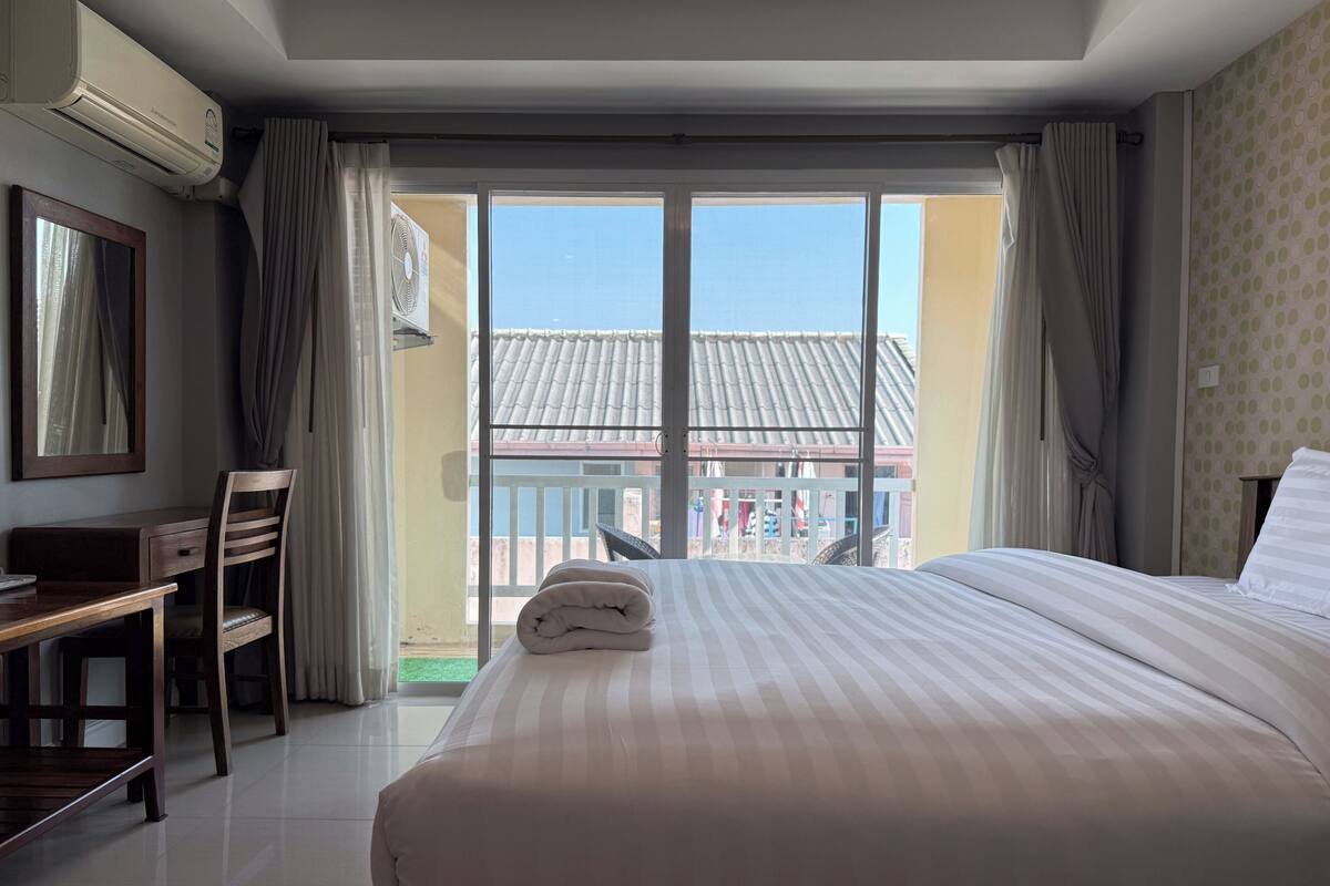 Une chambre d’hôtel avec un lit, un bureau, une chaise et une vue sur l’extérieur.