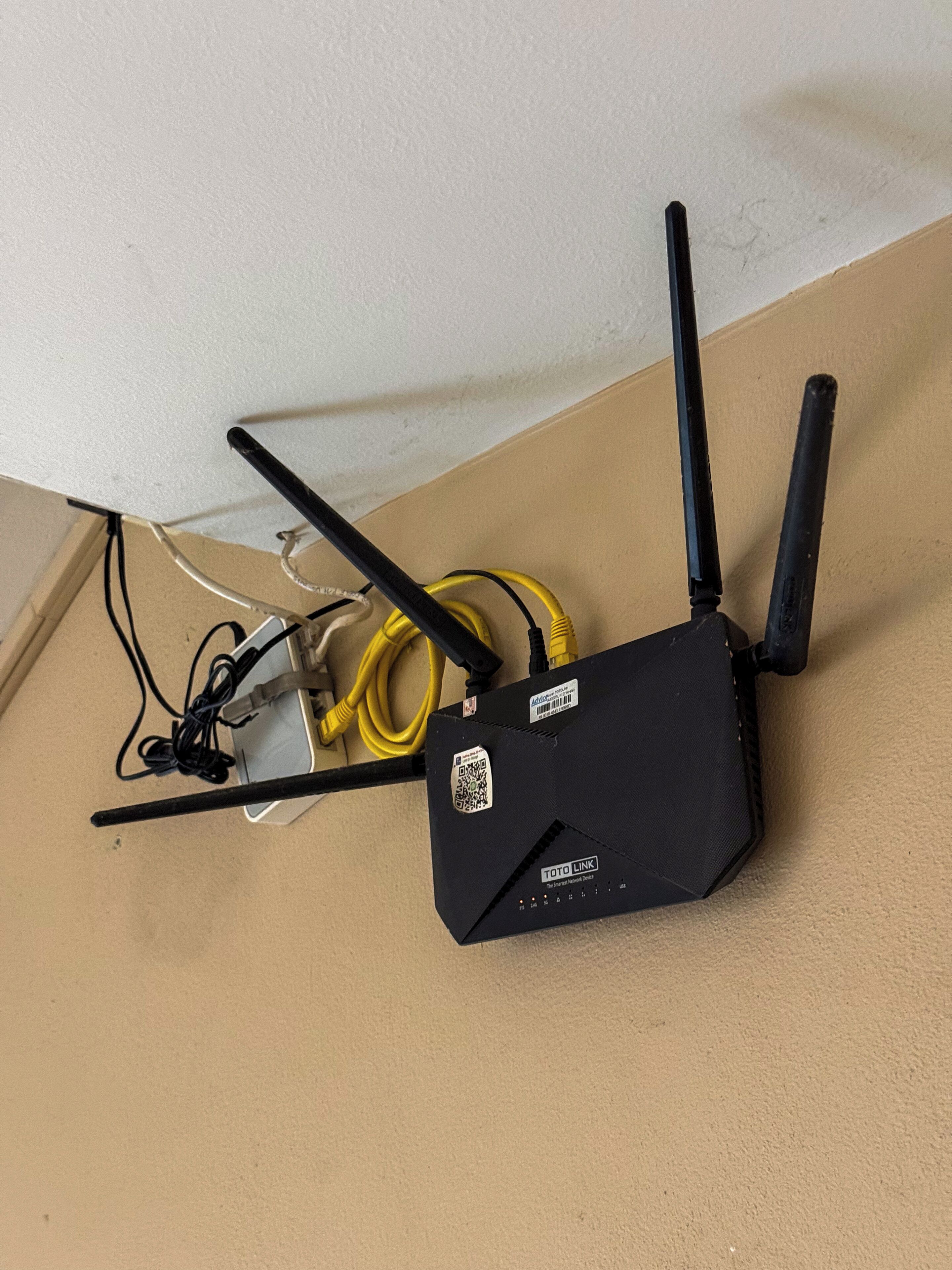 Un dispositivo de red negro con dos antenas y un cable amarillo conectado.