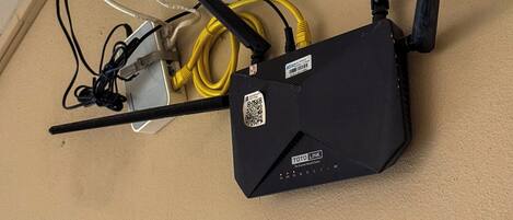 Un dispositivo de red negro con dos antenas y un cable amarillo conectado.