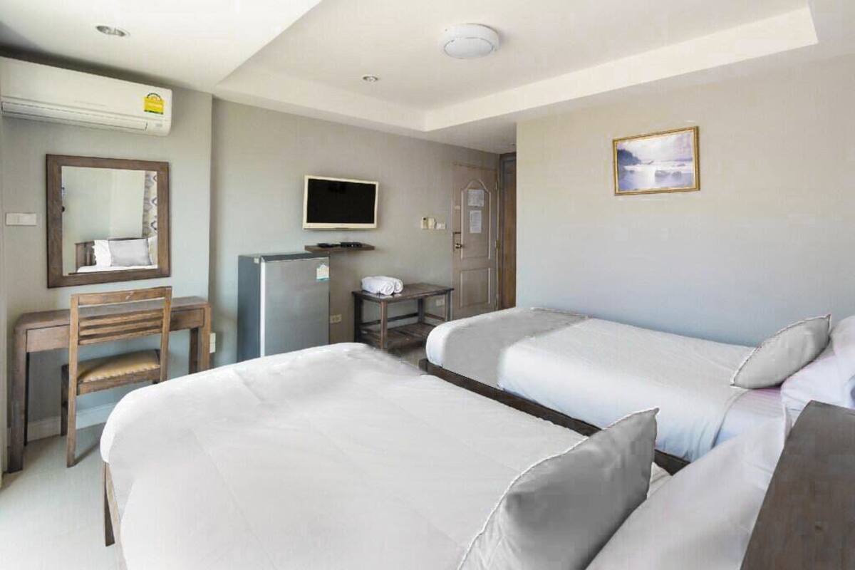 Une chambre d’hôtel avec deux lits, un bureau, une chaise, une télévision et une porte.