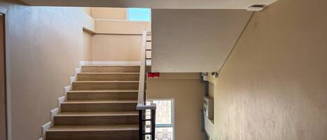 Una escalera con escalones de madera y una pared de color claro.