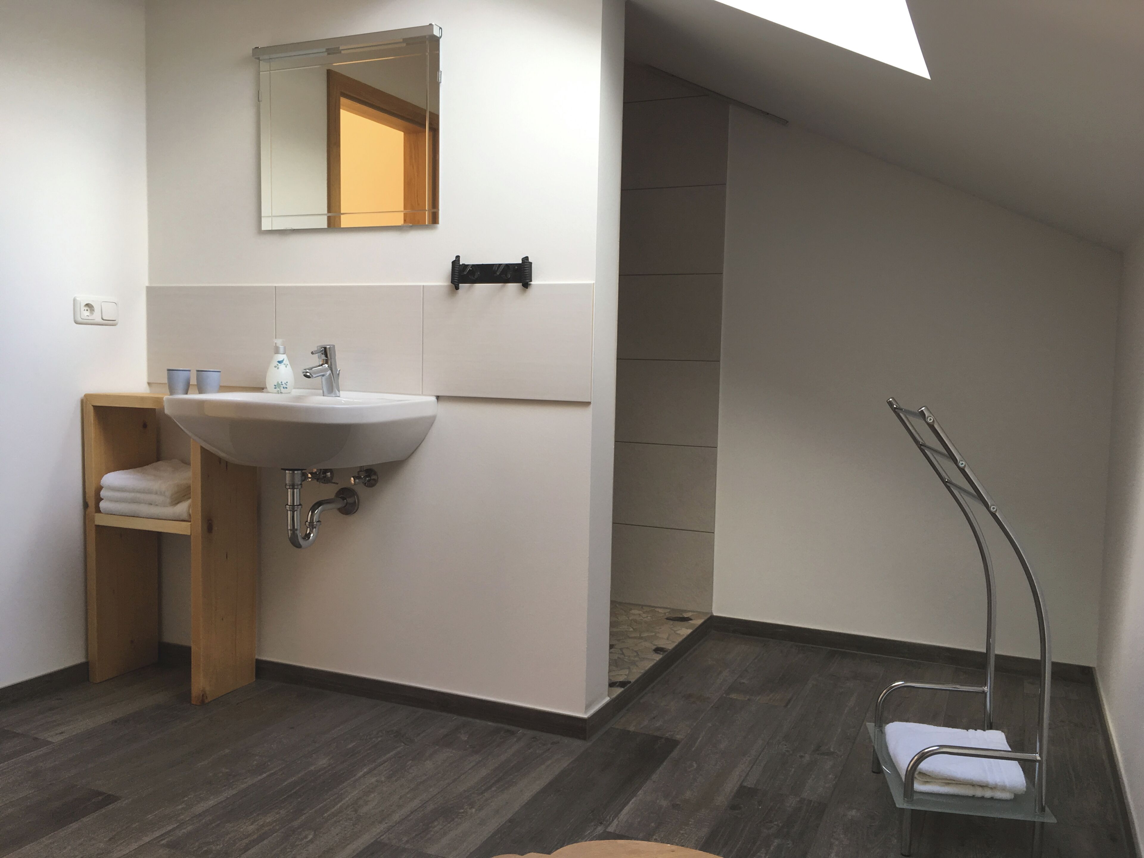 Un baño moderno con un lavamanos blanco, espejo y toallero.