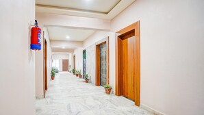 Un pasillo con suelo de mármol, puertas de madera y plantas en macetas.