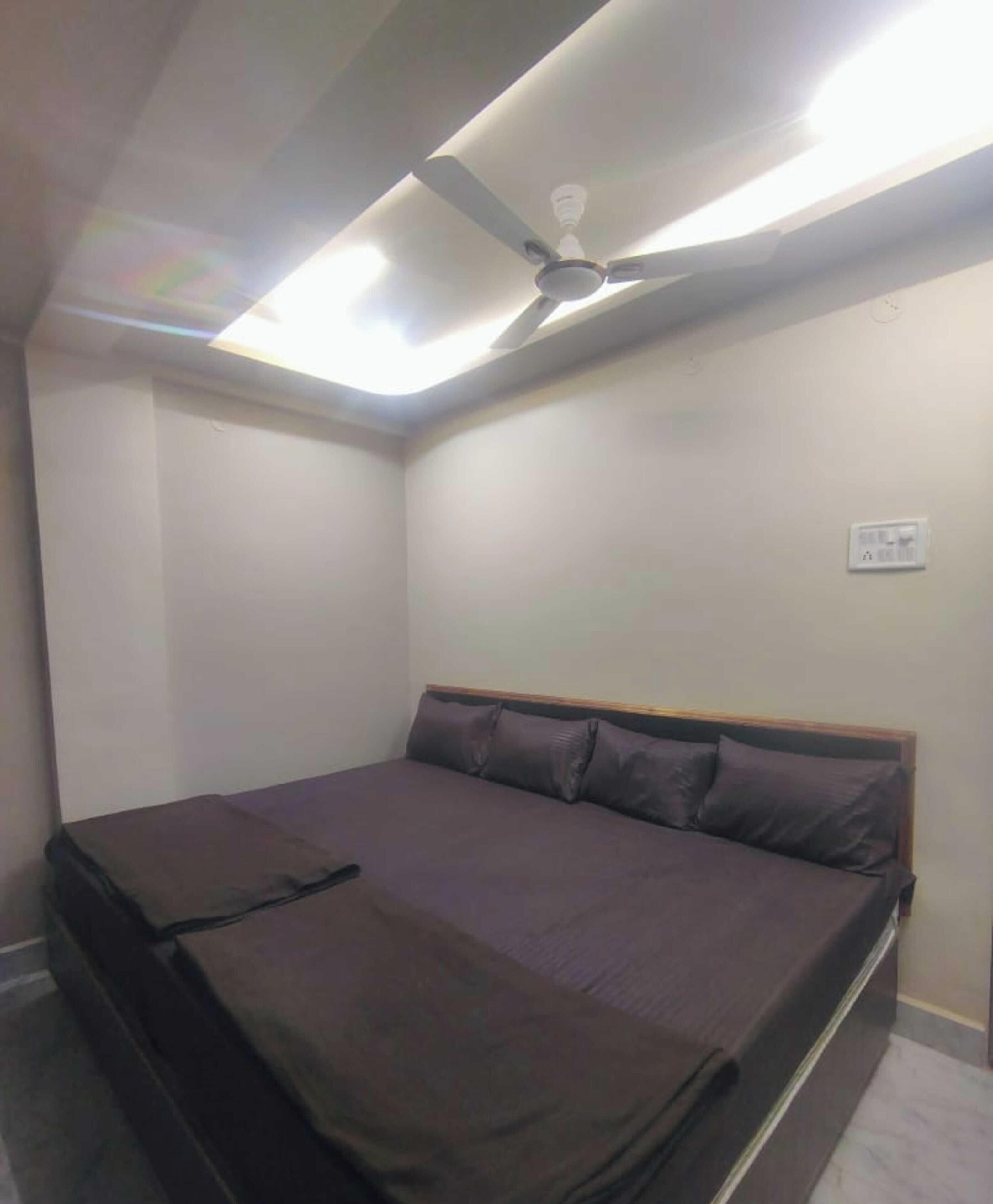 Una cama individual con cabecera, ventilador de techo y lámpara.