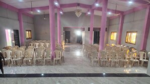 A spacious hall with rows of plastic chairs, marble flooring, and pink columns.