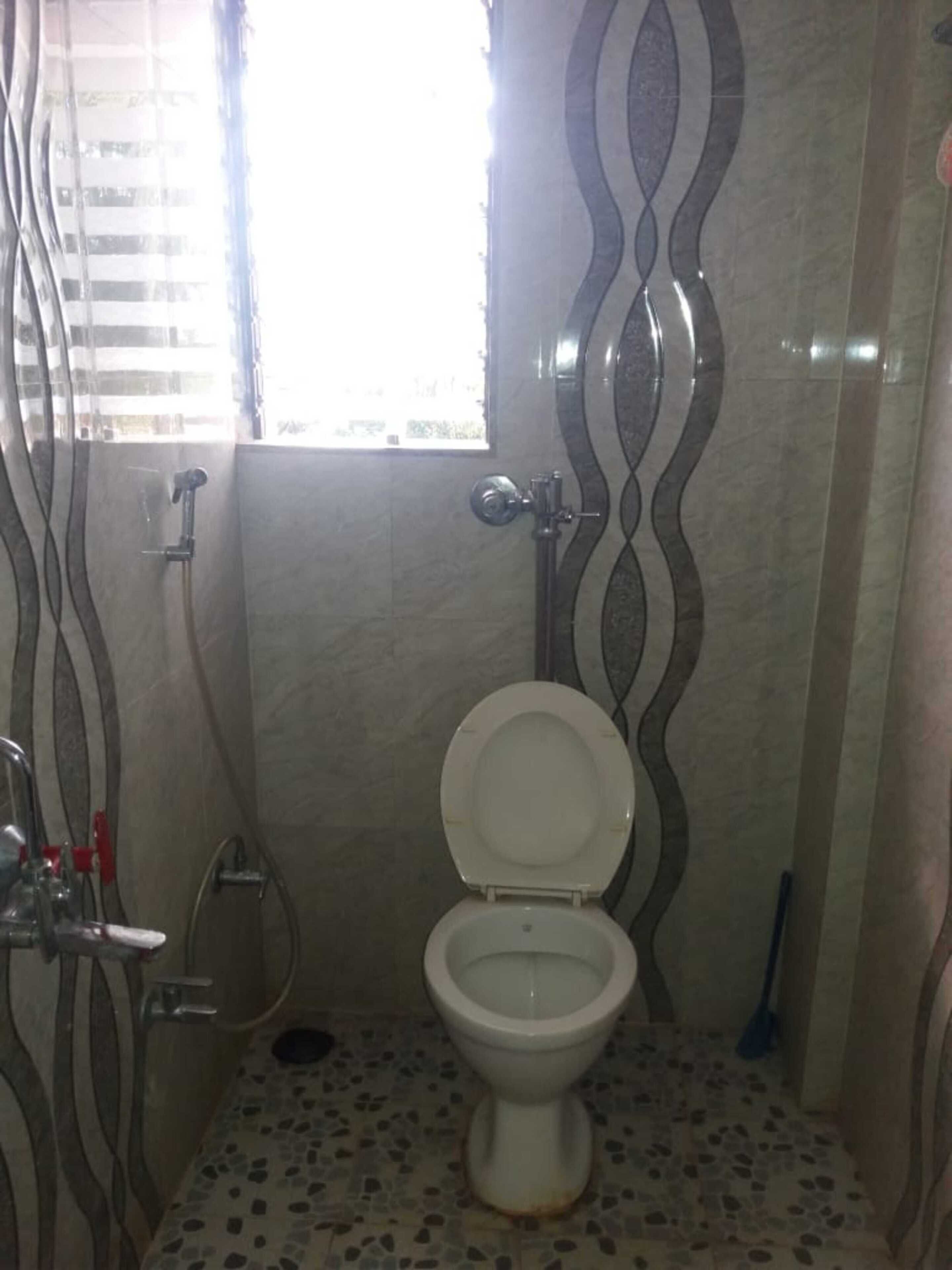 A bathroom with a toilet, a shower, and a window.
