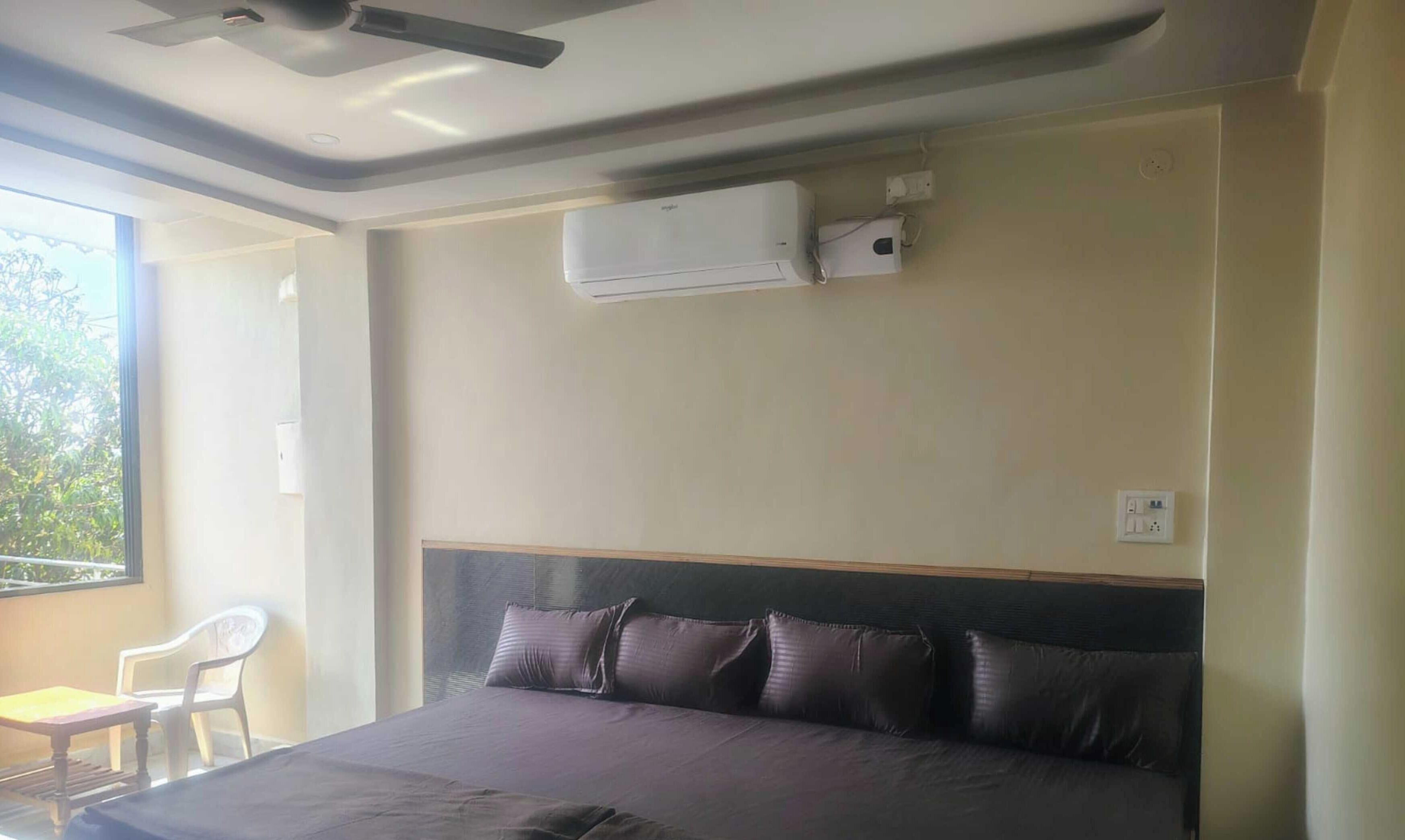 Ein Schlafzimmer mit einem Bett, einem Fenster, einem Sessel und einer Klimaanlage.