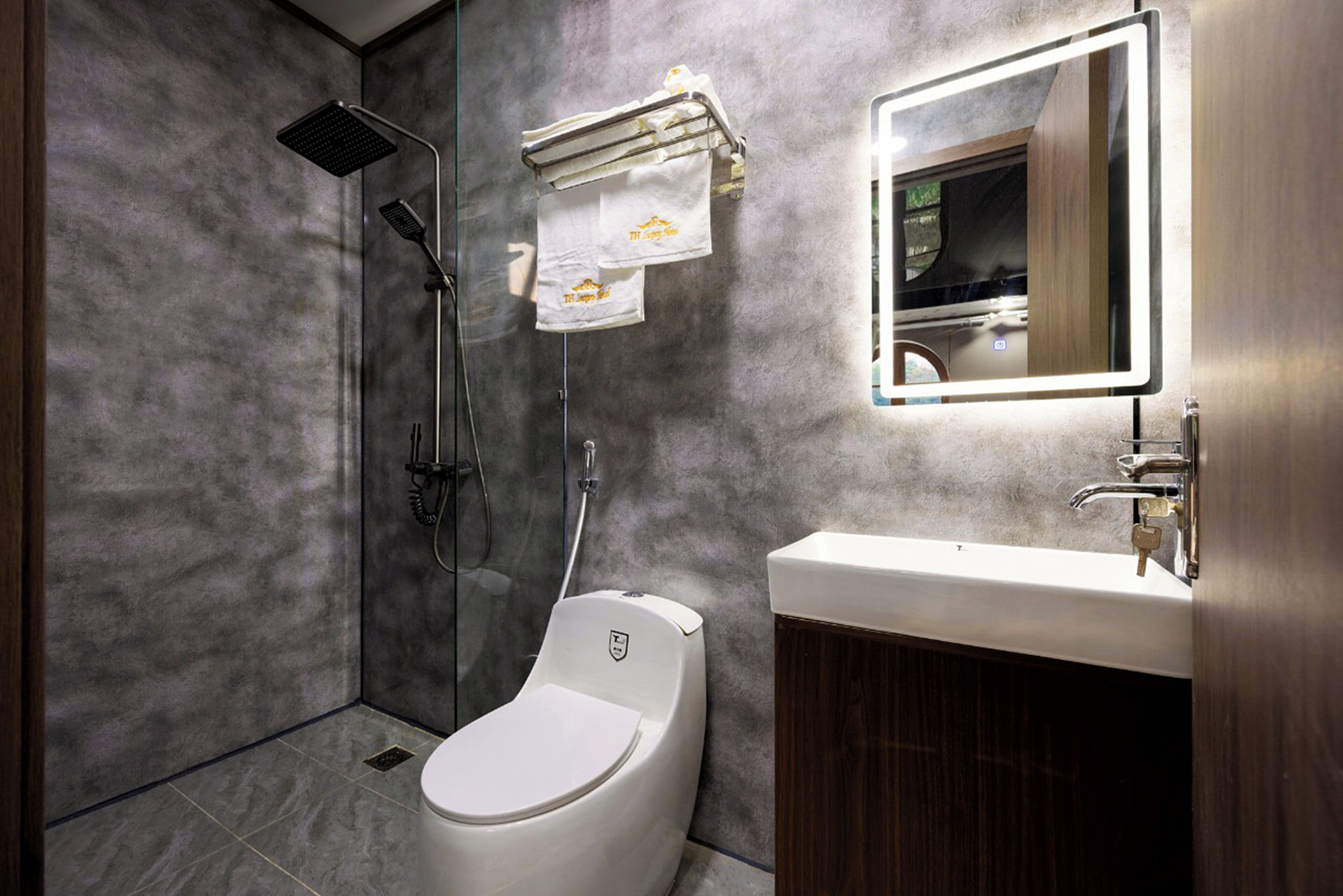 Un baño moderno con ducha, inodoro, lavabo y espejo con iluminación integrada.