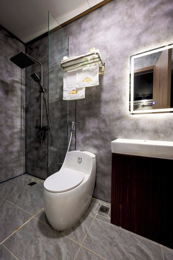 Une salle de bain moderne équipée de toilettes, d’une douche et d’un meuble-lavabo.