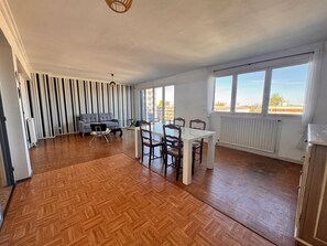 A spacious room with a dining table and chairs, a sofa, and a radiator. - Gaston's House — 40 m² apartment in Arras center (Arras)