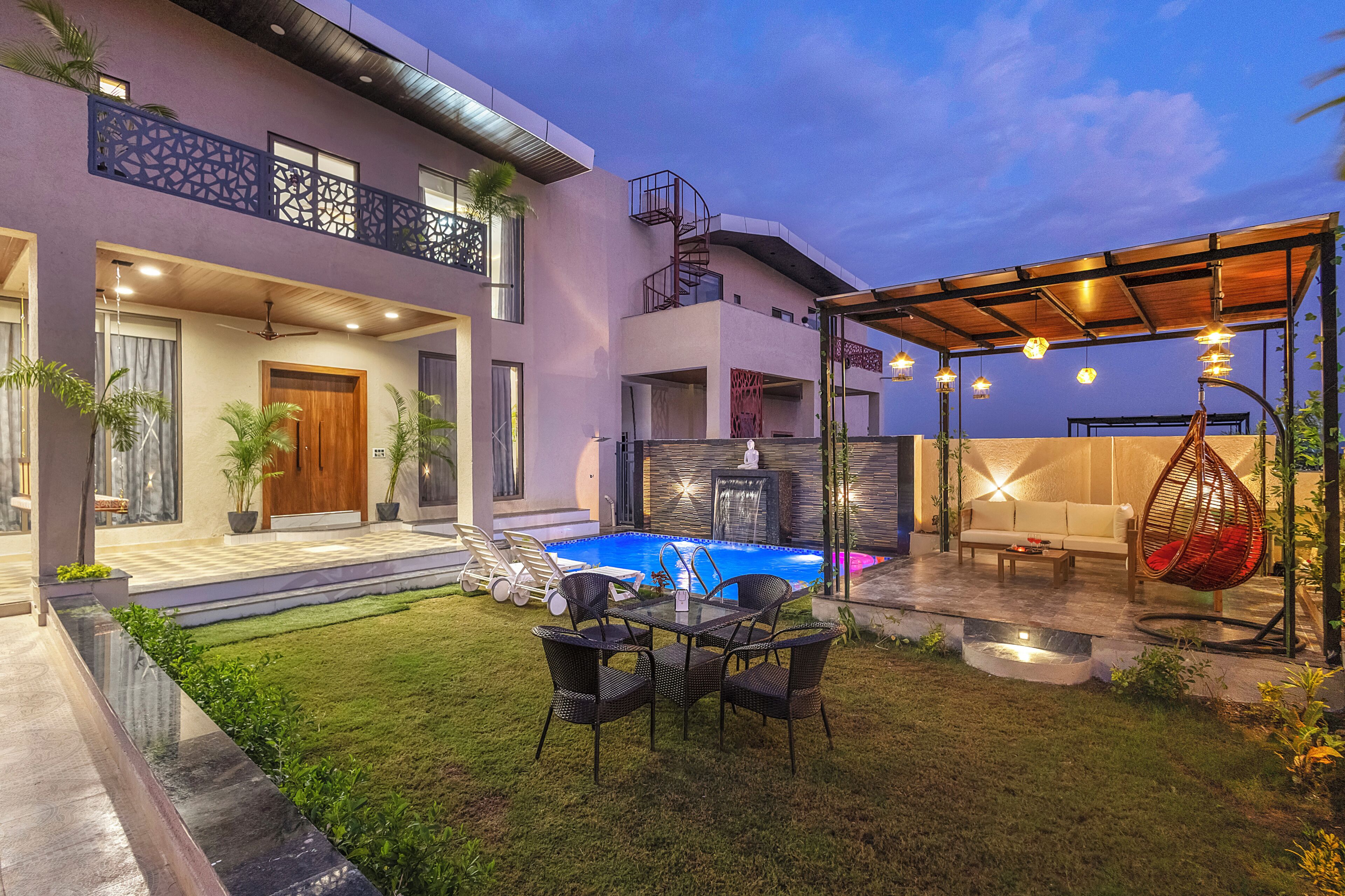 Una casa moderna con piscina, mobiliario exterior y un patio cubierto.