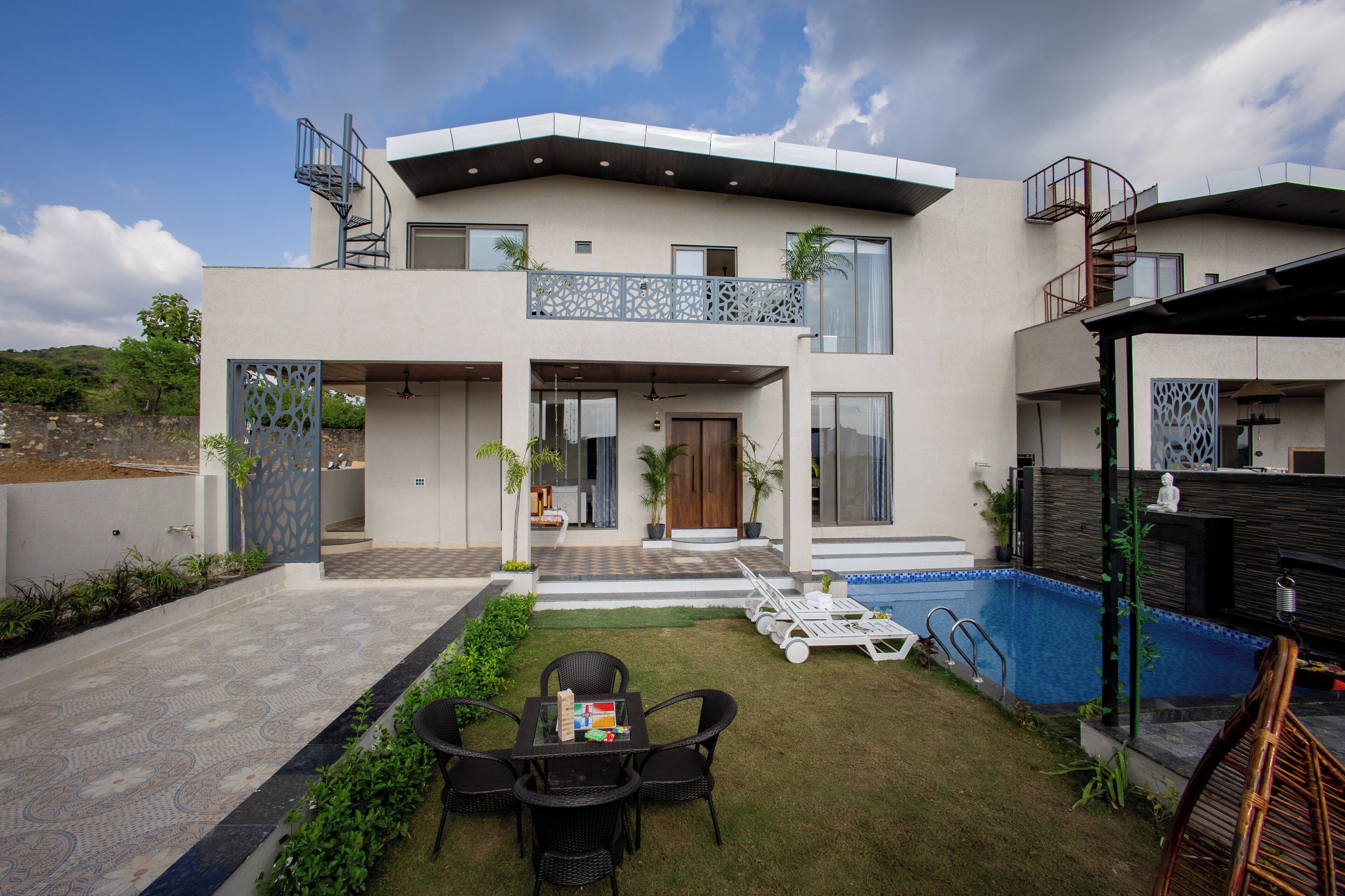 Een modern huis met twee verdiepingen, een balkon, een zwembad en een terras met tuinmeubilair.