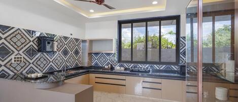 A modern kitchen with a built-in water dispenser, a ceiling fan, and a large window with a view of greenery.